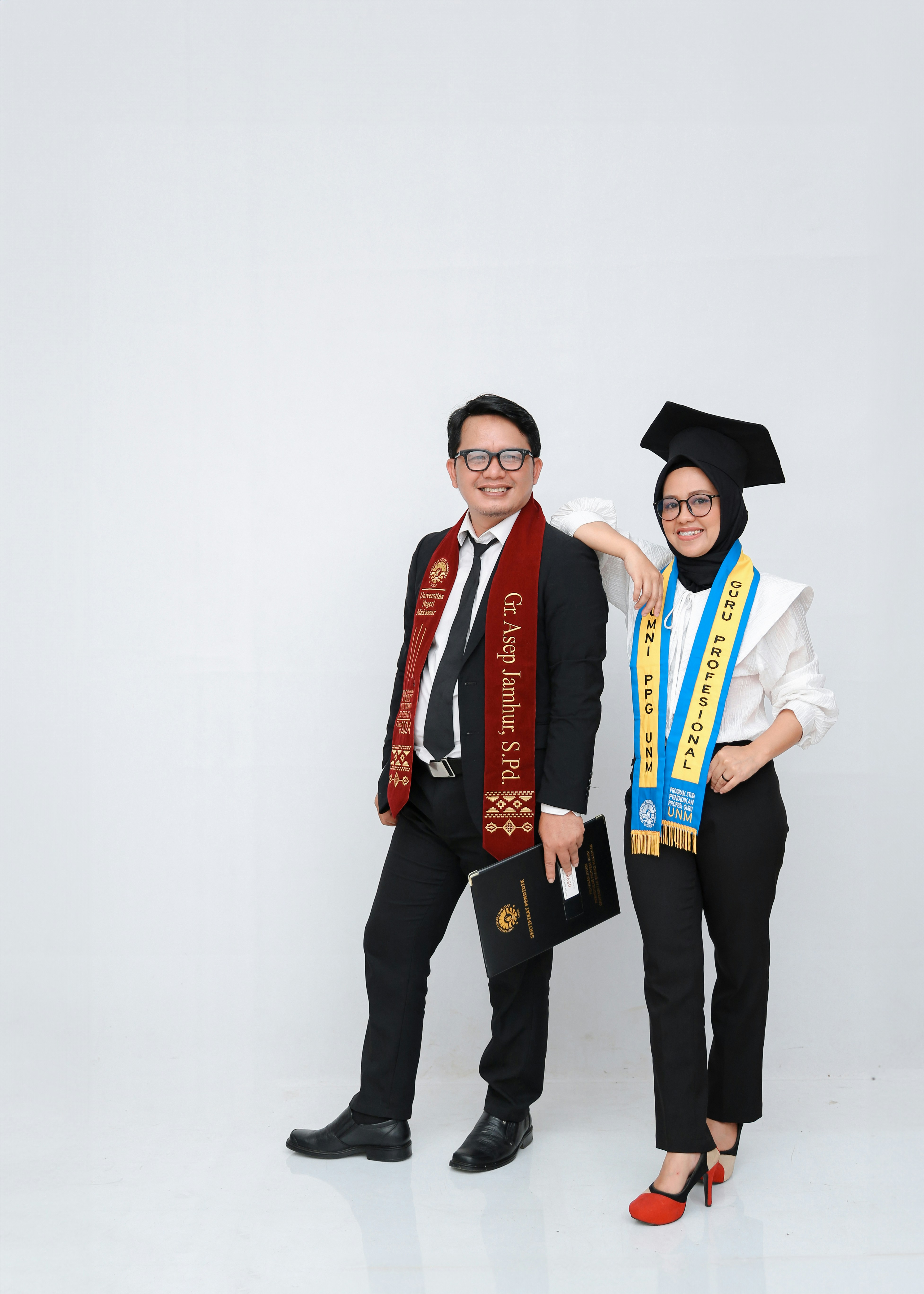 A couple in graduation attire posing for a studio portrait.